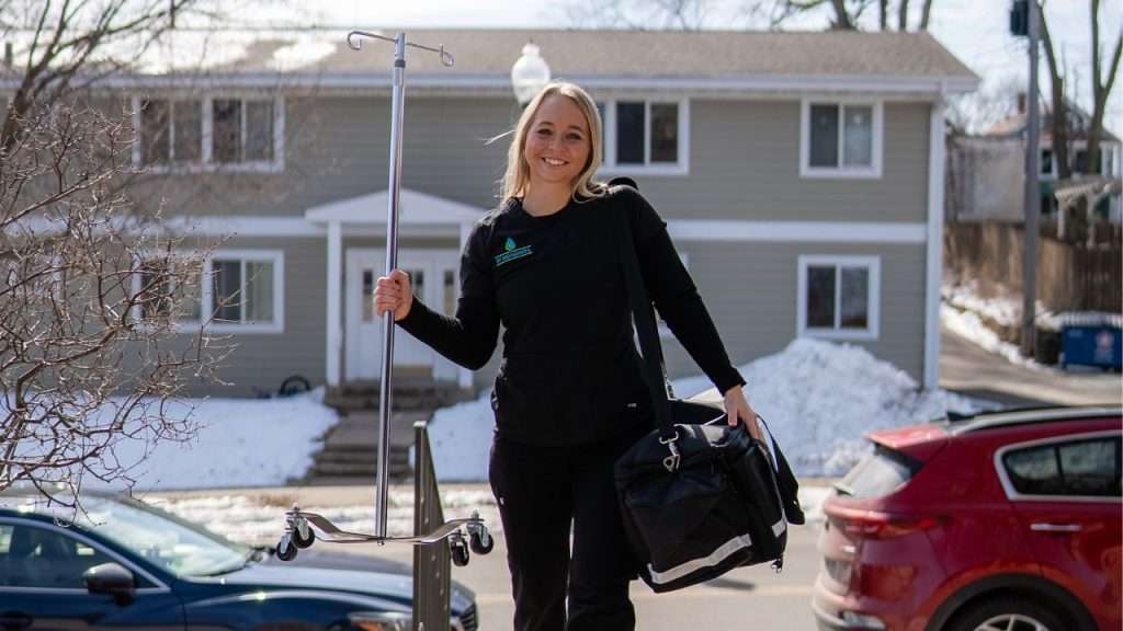 woman walking up with IV materials for in person IV appointment